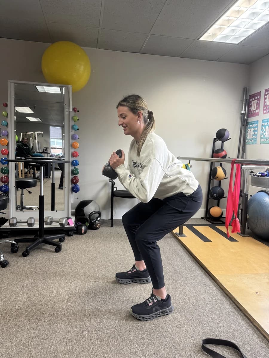 A woman performs a weighted squat inside a Fusion clinic.