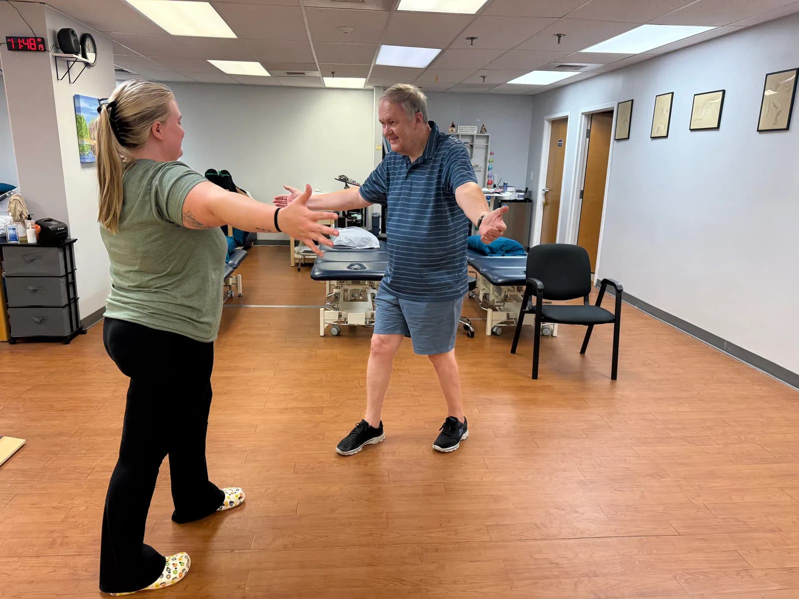 Two people practice a standing movement exercise in a Fusion treatment area.